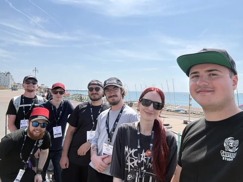 Seven of the Shiverbug team on Brighton seafront in the sun, wearing Develop:Brighton lanyards, some in studio t-shirts.